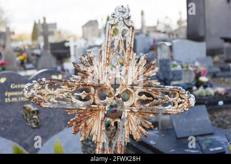 Une ancienne croix ornementale en métal rouillé sur une pierre tombale au cimetière Saint Roch. Valenciennes, France, 2017-01-05. Banque D'Images
