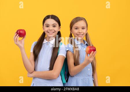 Les enfants heureux de l'école primaire ont de savoureuses pommes fruit jaune fond, snack d'école Banque D'Images