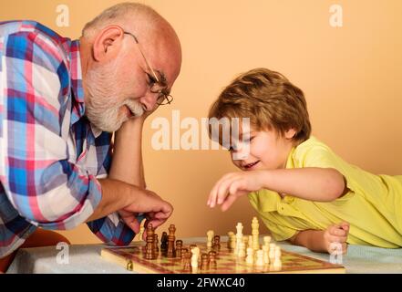 Enfant garçon développant une stratégie d'échecs. Grand-père et petit-fils jouant aux échecs. Développement du cerveau et concept logique. Banque D'Images