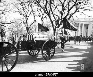 Le cortège funèbre du président John F. Kennedy quitte la Maison Blanche pour la cathédrale Saint-Matthieu l'Apôtre; le cercueil à pavillon du président Kennedy est supporté par un poisson tiré par des chevaux. Le cheval Riderless, Black Jack (dirigé par le soldat Arthur A. Carlson de première classe), marche à droite; les amateurs de tourniers et les membres de la garde de couleur bordent l'allée North Lawn. White House, Washington, D.C. Banque D'Images