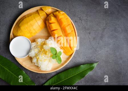 Riz mûr à la mangue cuit avec du lait de coco, riz Sticky fruits tropicaux d'été nourriture asiatique Thai dessert doux zeste de mangue et tranché sur l'assiette et min frais Banque D'Images