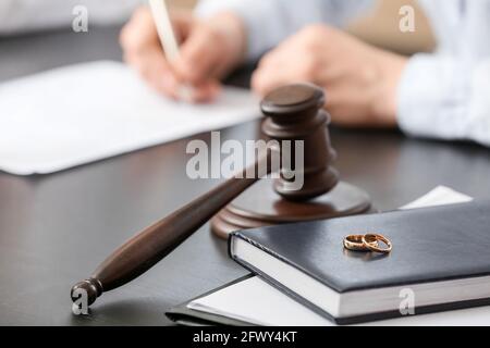 Le gavel du juge avec des anneaux et un livre sur table au bureau Banque D'Images