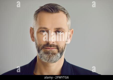 Portrait d'un homme d'affaires mature et confiant qui regarde l'appareil photo arrière-plan studio gris Banque D'Images