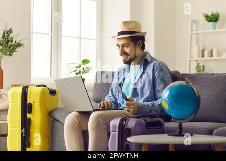 Homme en chapeau d'été utilisant un ordinateur portable pour la réservation d'hôtel ou réservation depuis la maison Banque D'Images