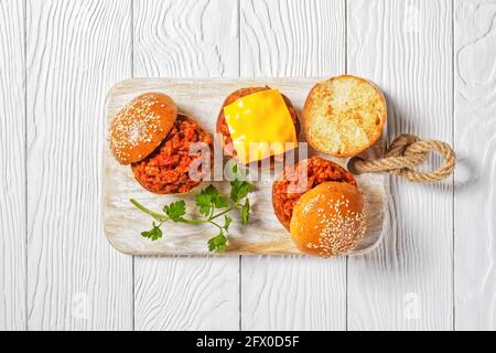 Sandwichs sloppy Joe sur brioches servis sur un panneau de bois blanc, gros plan, cuisine américaine Banque D'Images