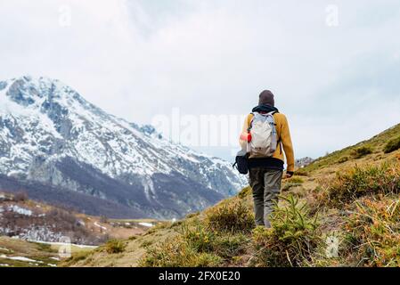 Vue arrière d'un touriste anonyme avec sac à dos sur la neige Pelouse dans la vallée des montagnes dans les sommets de l'Europe Banque D'Images