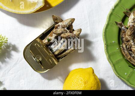 De dessus des anchois frits et en conserve servis sur table avec des citrons frais au restaurant en plein soleil Banque D'Images