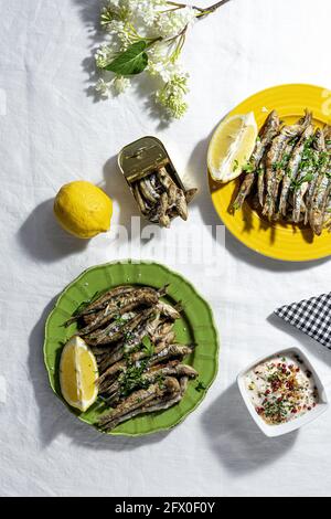 De dessus des anchois frits et en conserve servis sur table avec des citrons frais au restaurant en plein soleil Banque D'Images