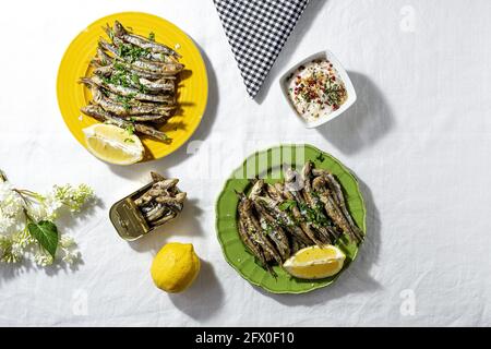 De dessus des anchois frits et en conserve servis sur table avec des citrons frais au restaurant en plein soleil Banque D'Images