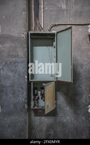 Vider l'ancien tableau de commutation. Ouvrir la boîte du panneau de distribution sur un mur en béton endommagé dans un bâtiment abandonné Banque D'Images