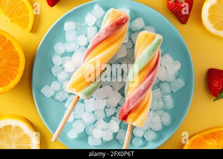 Pop-sicle en spirale colorée avec fruit sur fond jaune Banque D'Images