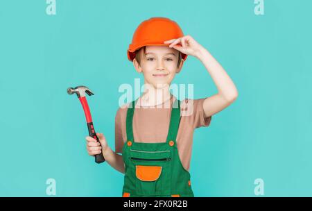 Petit constructeur en casque et hummer. Enfant habillé comme un ouvrier de construction. Petit garçon portant un casque. Portrait petit constructeur en casque marteau. Enfant Banque D'Images