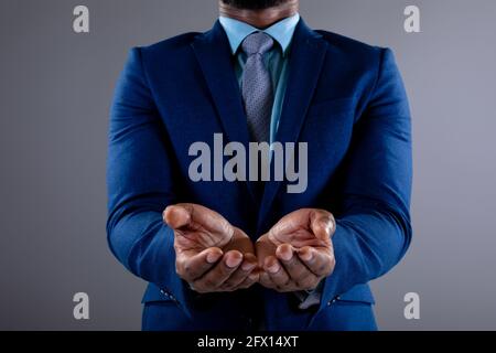 Section moyenne d'homme d'affaires afro-américain avec les mains contre arrière-plan gris Banque D'Images