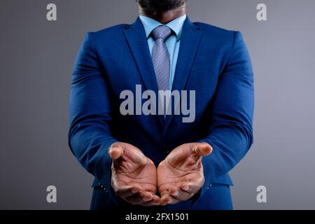 Section moyenne d'homme d'affaires afro-américain avec les mains contre arrière-plan gris Banque D'Images