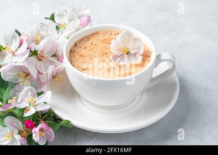 Tasse à café blanche et fleurs en gros plan sur fond gris. Banque D'Images