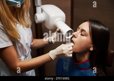 Personne médicale vérifiant les dents du patient à l'aide d'un dispositif à rayons X. Banque D'Images