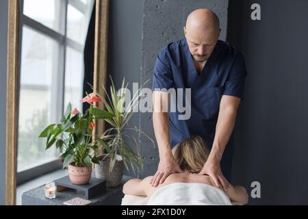 mains masculines du masseur pendant la séance de massage - thérapie manuelle de la femme de retour Banque D'Images