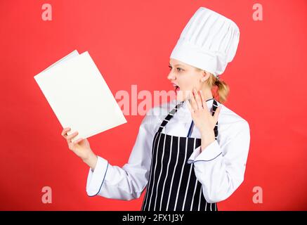 chef professionnel dans la cuisine. Cuisine. Happy Woman cuisant des aliments sains par recette. Menu du restaurant. Le régime culinaire. Femme de ménage avec livre de cuisine Banque D'Images