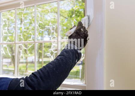 Rénovation à la maison dans les peintures de handyman avec un pinceau un cadre de moulure de vitre Banque D'Images