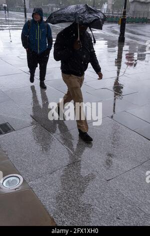 Les Londoniens mouillés marchent le long de la zone pavée à l'extérieur de la National Gallery pendant les précipitations saisonnières de printemps, le 24 mai 2021, à Londres, en Angleterre. Banque D'Images