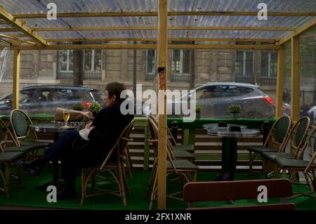 Une parisienne prend un verre le soir sur une terrasse temporaire du café de Paris, construite pour permettre aux clients de boire dehors après la levée des restrictions Covid-19 - le Montmartre café, rue Custine, 75018, Paris, France Banque D'Images