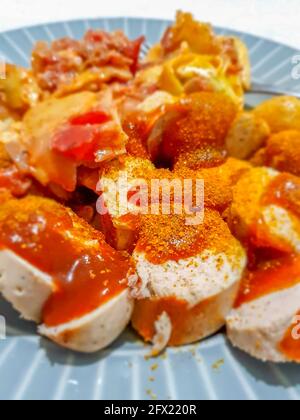 Currywurst allemand - morceaux de Bratwurst allemand curry, saucisse avec ketchup et currypowder sur une assiette Banque D'Images