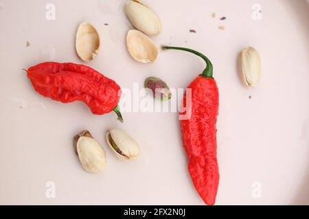 Vue sur les Chiles rouges et les pistaches sur la crème assiette rose clair Banque D'Images