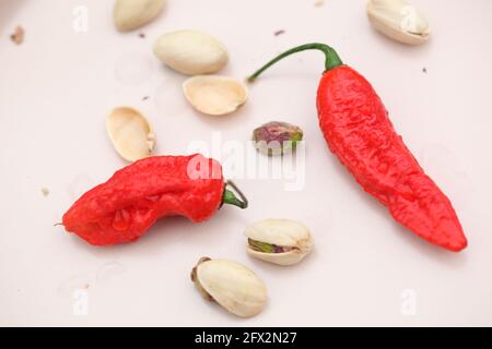 Vue sur les Chiles rouges et les pistaches sur la crème céramique rose clair Banque D'Images