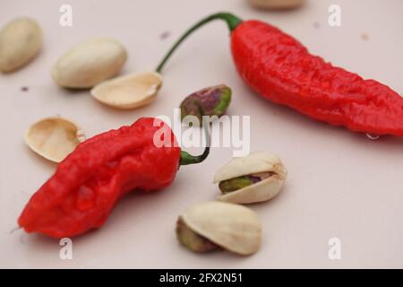 Vue sur les Chiles rouges et les pistaches sur la crème arrière-plan rose clair Banque D'Images