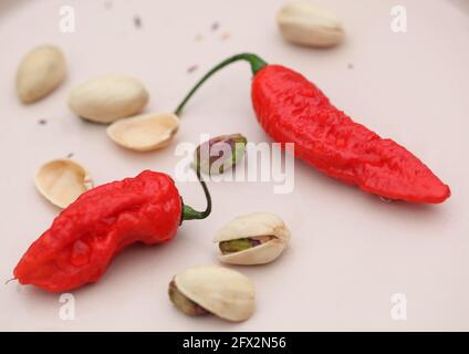 Vue sur les Chiles rouges et les pistaches sur la crème arrière-plan rose clair Banque D'Images