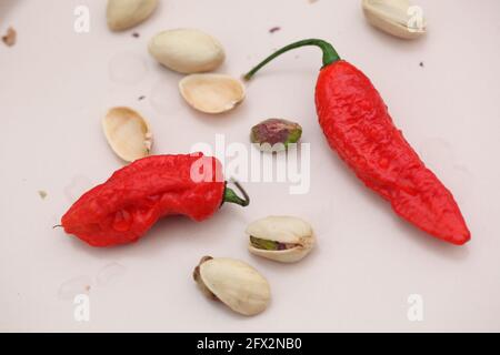 Vue sur les Chiles rouges et les pistaches sur la crème arrière-plan rose clair Banque D'Images