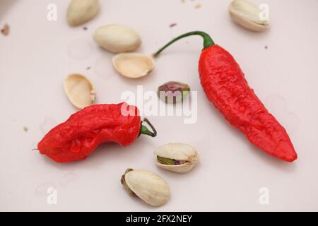 Vue sur les Chiles rouges et les pistaches sur la crème céramique rose clair Banque D'Images