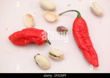 Vue sur les Chiles rouges et les pistaches sur la crème céramique rose clair Banque D'Images