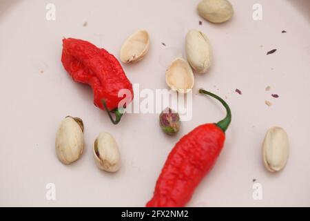 Vue sur les Chiles rouges et les pistaches sur la crème céramique rose clair Banque D'Images