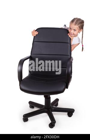 Chaise de bureau chaise de bureau et petite fille joyeuse isolée sur fond blanc. Chaise moderne réglable en cuir noir. Banque D'Images