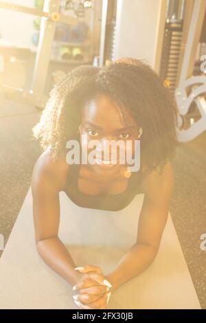 Jeune femme lumineuse sur un tapis de yoga. Gros plan, en regardant l'appareil photo, fitness, ARMS Cross, afro-américain, femme noire, portrait, tapis de yoga Banque D'Images