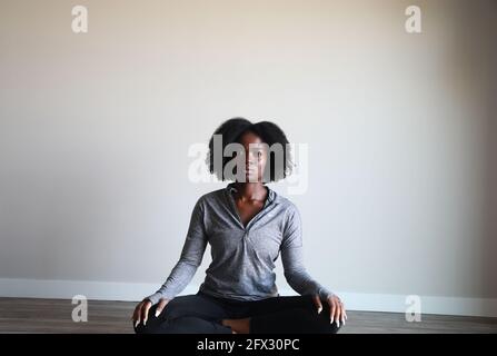 Portrait d'une jeune femme à la peau sombre et attrayante en vêtements de sport méditant à l'intérieur, une personne, santé, vie active, afro-américain, Banque D'Images