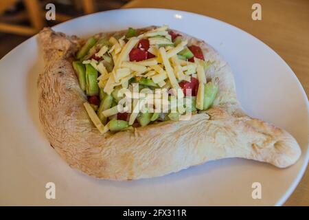 Portion de Khachapuri adjarien avec légumes, spécialité de la Géorgie Banque D'Images