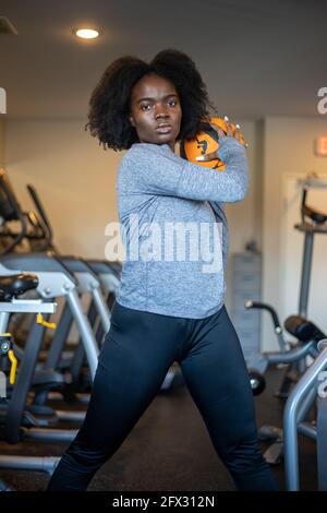 Faire de l'exercice sportif fille avec le ballon de fitness, levage, une personne, gros plan, femme noire, afro-américain, fond, centre de fitness Banque D'Images