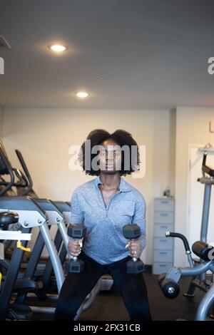 Jeune femme faisant des fentes et de l'exercice de squat dans la salle de gym. Gros plan, une personne, Afro-américain, femme noire, fitness, arrière-plan, haltères, cheveux naturels, Banque D'Images