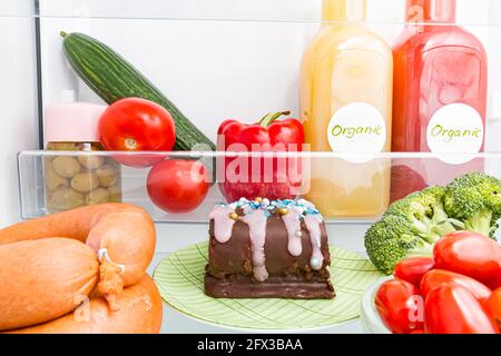 Réfrigérateur en gros plan de l'intérieur, étagères en verre avec plats colorés, desserts, bouteilles de boissons, légumes, saucisses. Réfrigérateur rempli de nourriture. Banque D'Images