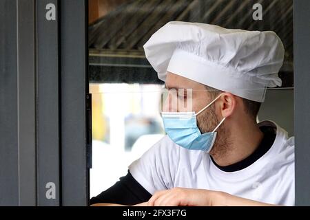 Un jeune chef portant un masque Covid pendant une pause de travail. Milan, Italie - mai 2021 Banque D'Images