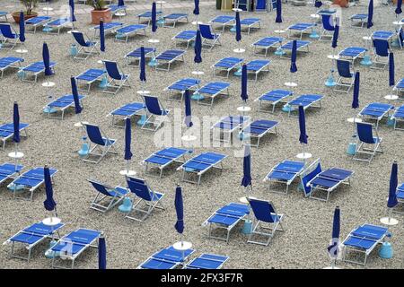 Chaises longues de plage vides avec parasols pliés en Italie Banque D'Images