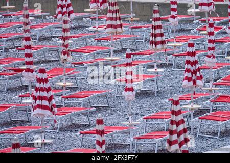 Chaises longues de plage vides avec parasols pliés en Italie Banque D'Images