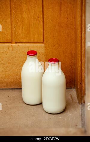 Deux pintes de lait frais dans des biberons traditionnels en verre à une porte Banque D'Images