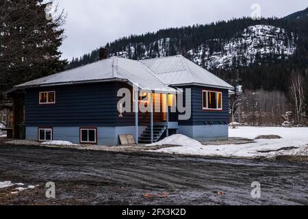 REVELSTOKE, CANADA - le 14 MARS 2021 : maison privée et vue sur la rue dans une petite ville en soirée, tôt le printemps avec de la neige Banque D'Images