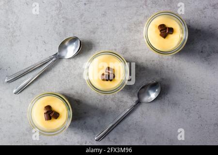 Trois verres de pudding à la vanille disposés vers le haut ligne diagonale sur le comptoir gris Banque D'Images