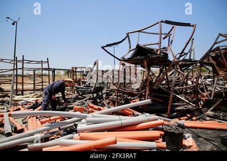 Gaza, Palestine. 25 mai 2021. Un travailleur palestinien sauve des articles dans une usine de tuyaux en plastique endommagée dans la zone industrielle de Gaza à la suite des frappes israéliennes.la diplomate américaine Antony Blinken a exprimé son vœu de soutenir la reconstruction de la bande de Gaza dévastée et d'encourager une trêve entre le Hamas et Israël, Mais a insisté sur le fait que les dirigeants militants islamistes du territoire ne bénéficieraient d'aucune aide. Crédit : SOPA Images Limited/Alamy Live News Banque D'Images