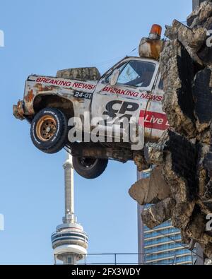 Installation d'œuvres d'art dans la station de télévision locale CP24, Toronto, Canada. Une voiture est vue par le mur. Ses roues tournent toujours, ce qui signifie que les nouvelles le sont toujours Banque D'Images