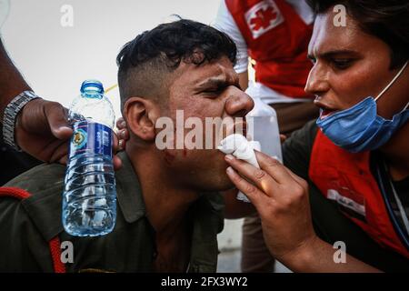 Bagdad, Irak. 25 mai 2021. Un membre des forces de sécurité irakiennes reçoit un traitement lors d'affrontements à la suite d'une manifestation anti-gouvernementale demandant la révélation des tueurs d'activistes pro-réformes. Credit: Ameer Al Mohmedaw/dpa/Alamy Live News Banque D'Images